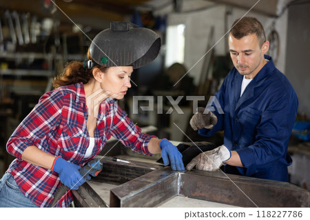 Foreman points out the poor-quality weld that the woman made. Working moments at metal structures assembly plant 118227786