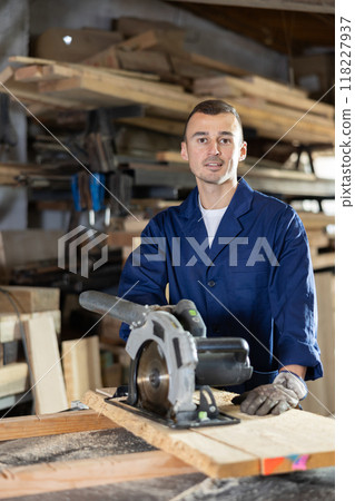 Young man saws oak plank in workshop 118227937