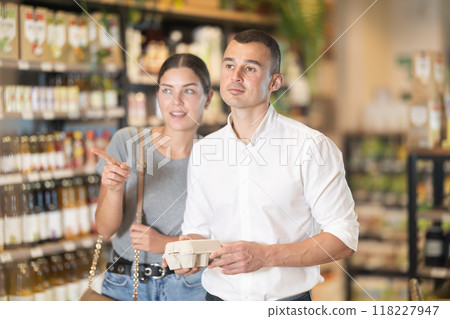 Man with package of eggs in hands talks with wife about buying ingredients for making homemade pie. Man with package of eggs in hands talks with wife about buying ingredients for making homemade pie. 118227947