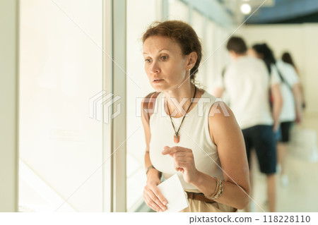 Woman looks at museum exhibit with brochure 118228110