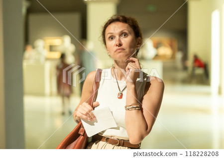 Woman looks at museum sculptures with brochure Woman looks at museum sculptures with brochure 118228208