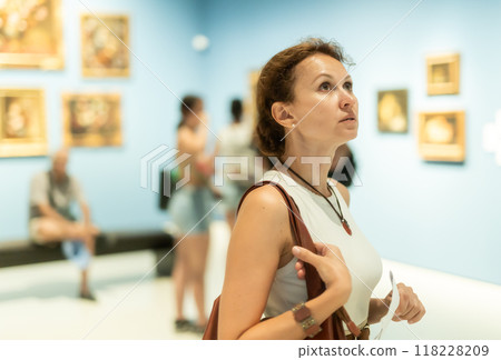 Portrait of beautiful woman looking at pictures and amaze in museum, holding guide book Portrait of beautiful woman looking at pictures and amaze in museum, holding guide book 118228209