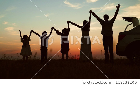 Big family at sunset holding hands, silhouettes. Happy people children parents lined up according to height held hands raised in air with joyful cheerful feeling of freedom anticipation of journey. Big family at sunset holding hands, silhouettes. Happy people children parents lined up according to height held hands raised in air with joyful cheerful feeling of freedom anticipation of journey. 118232109