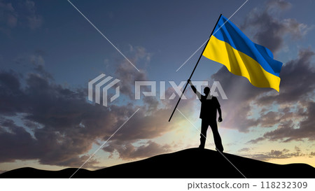 The silhouette of a man, standing on a small mountain, waves the Ukrainian flag, in the background a cloudy sky at dawn 118232309