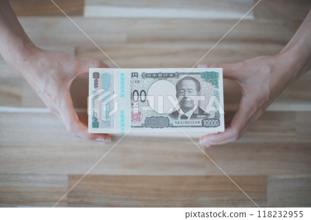A person's hand holding a stack of Japanese yen bills 118232955