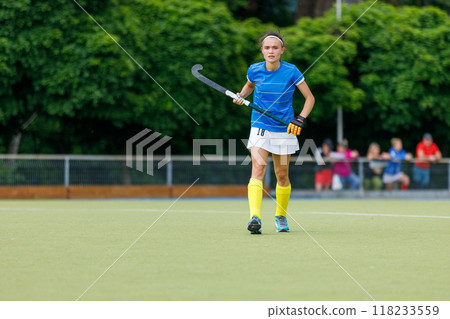 Young female athlete playing field hockey on a sunny day in a vibrant park Young female athlete playing field hockey on a sunny day in a vibrant park 118233559