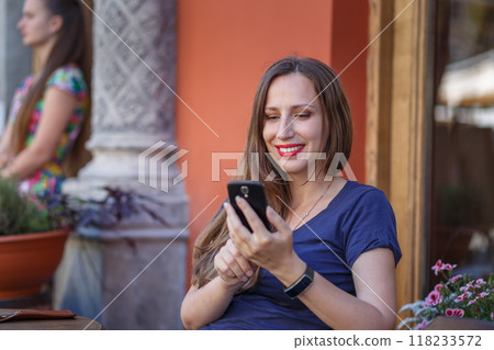 Young woman enjoying videocall while sitting at cafe outdoors in summer Young woman enjoying videocall while sitting at cafe outdoors in summer 118233572