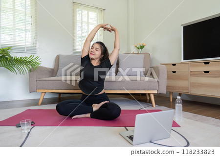 Woman practicing yoga and stretching at home with laptop 118233823