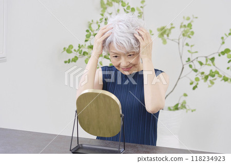Elderly woman fixing her hair Elderly woman fixing her hair 118234923