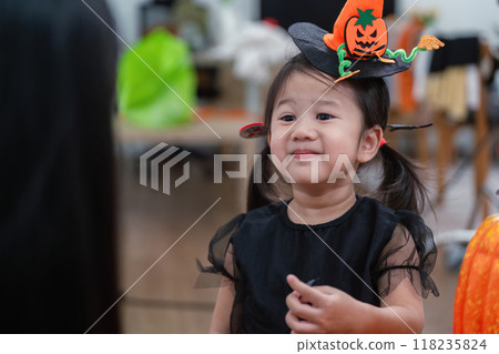 Asian toddler in Halloween attire with mother enjoying festive decor 118235824