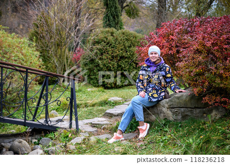 Carefree young woman in trendy vintage pants sitting on table in 118236218