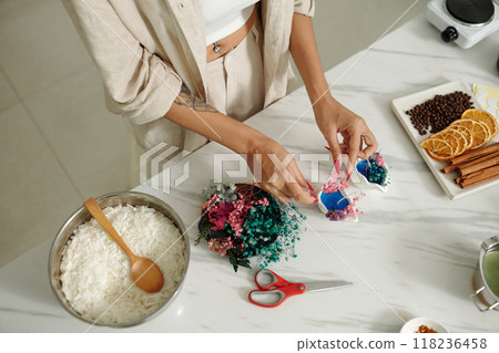 Woman Using Dried Flowers To Decorate Candles Woman Using Dried Flowers To Decorate Candles 118236458