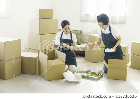 Two female movers doing moving work Two female movers doing moving work 118236520