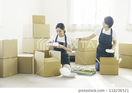 Two female movers doing moving work Two female movers doing moving work 118236521