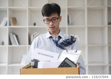 Disappointed Businessman Holding Resignation Letter and Packing Belongings 118237044