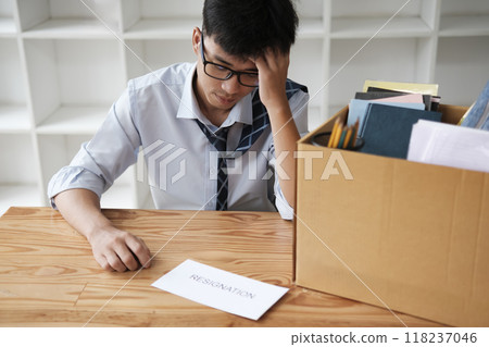 Disappointed Businessman Holding Resignation Letter and Packing Belongings 118237046