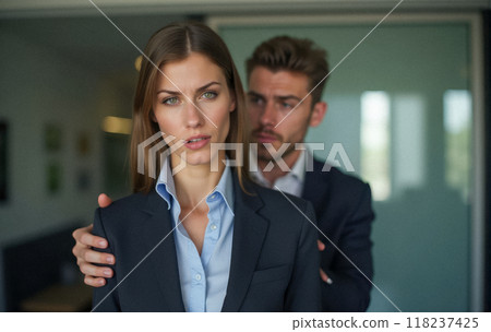 Harassment in corporate setting, male boss places hand on young female employee shoulder. Woman in formal attire visibly uncomfortable, unwanted physical contact Harassment in corporate setting, male boss places hand on young female employee shoulder. Woman in formal attire visibly uncomfortable, unwanted physical contact 118237425