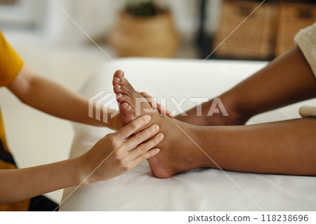 Providing Relaxing Foot Massage in Cozy Spa Setting 118238696