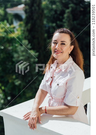 Beautiful woman of 40 years old sitting on the balcony and smiling Beautiful woman of 40 years old sitting on the balcony and smiling 118239501