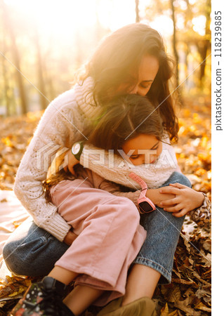 Stylish young Mother and daughter walking in the autumn forest at sunset. Family on a walk. 118239885
