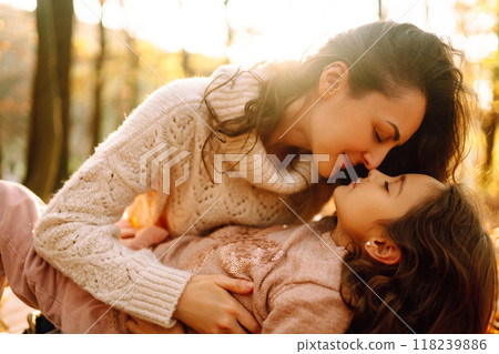 Stylish young Mother and daughter walking in the autumn forest at sunset. Family on a walk. 118239886