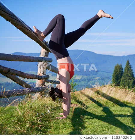 Woman practicing yoga outdoors in the mountains in a serene, natural setting. Female performing yoga pose on mat, with backdrop of beautiful mountain landscape at sunrise or sunset. Woman practicing yoga outdoors in the mountains in a serene, natural setting. Female performing yoga pose on mat, with backdrop of beautiful mountain landscape at sunrise or sunset. 118240260