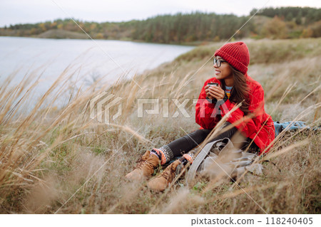 Beautiful woman drinking tea from thermos on cold autumn day. Rest, relaxation, lifestyle concept. 118240405