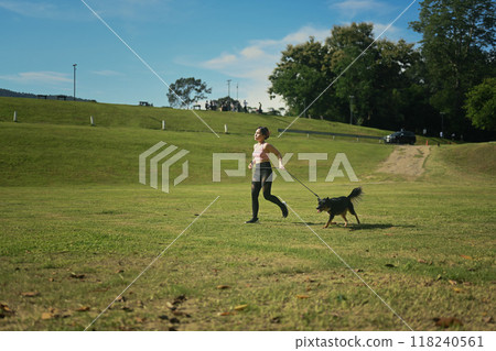 Young woman jogging with her dog on a beautiful sunny day. Outdoor activities and the bond between owner and their dog 118240561