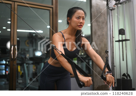 Determined athletic young woman working out in a gym, using a cable machine Determined athletic young woman working out in a gym, using a cable machine 118240628