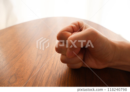 A woman's clenched fist on a desk A woman's clenched fist on a desk 118240798