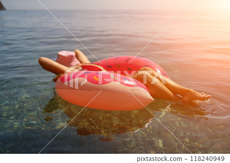 Summer vacation woman in hat floats on an inflatable donut mattress. Happy woman relaxing and enjoying family summer travel holidays travel on the sea. 118240949