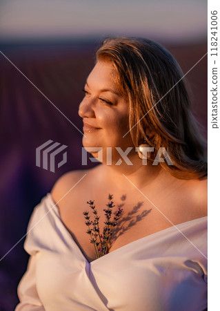 woman poses in lavender field at sunset. Happy woman in white dress holds lavender bouquet. Aromatherapy concept, lavender oil, photo session in lavender 118241006