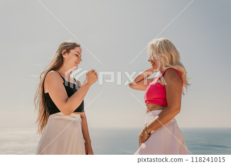 Two women shake hands on a beach 118241015