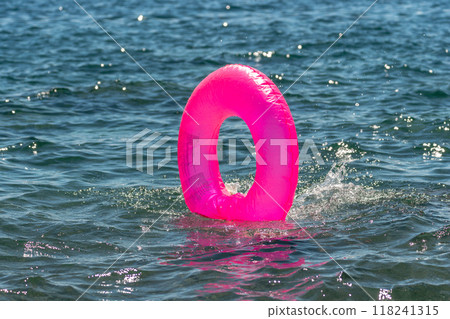 Inflatable Ring Water Safety Beach - Pink inflatable ring floating in the water for safety. 118241315