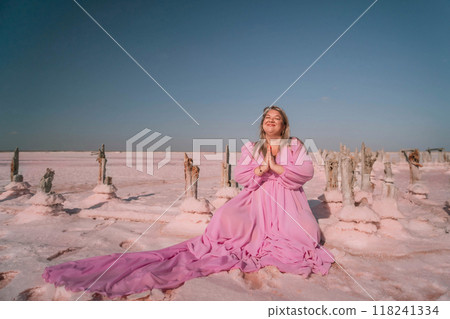Woman Pink Dress Salt Flats Praying in Pink Desert Landscape. Woman Pink Dress Salt Flats Praying in Pink Desert Landscape. 118241334