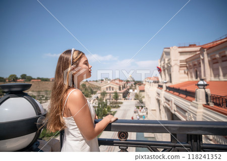 Woman Balcony View Cityscape - Young woman enjoying a view of the city from a balcony. 118241352