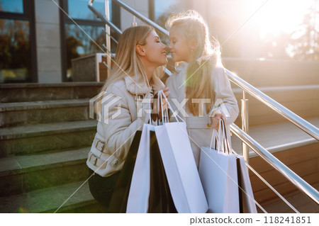 Young mother and little girl with shopping bags after shopping. Spring Style. Consumerism. Young mother and little girl with shopping bags after shopping. Spring Style. Consumerism. 118241851