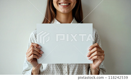 Young woman holding blank sheet of paper smiling 118242539