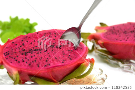 Spoon inserted into red dragon fruit on a glass plate 118242585
