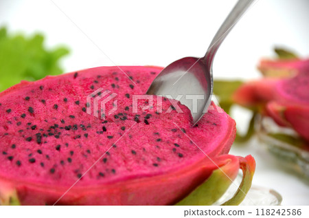 Spoon inserted into red dragon fruit on a glass plate 118242586