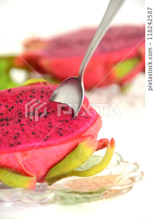 Spoon inserted into red dragon fruit on a glass plate 118242587