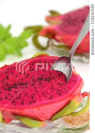 Spoon inserted into red dragon fruit on a glass plate 118242589