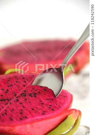Spoon inserted into red dragon fruit on a glass plate 118242590