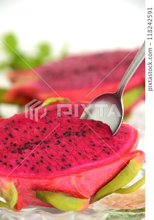 Spoon inserted into red dragon fruit on a glass plate 118242591