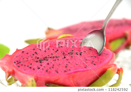 Spoon inserted into red dragon fruit on a glass plate 118242592