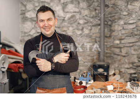 Portrait of a nature craftsman looking in camera and posing for a photo. Man wearing an apron. Grounge dark stone texture background. 118243676
