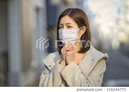 Middle-aged woman walking outdoors wearing a mask 118244773