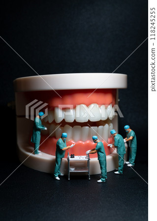 Miniature figurines of surgeons working on a large model of human teeth Miniature figurines of surgeons working on a large model of human teeth 118245255