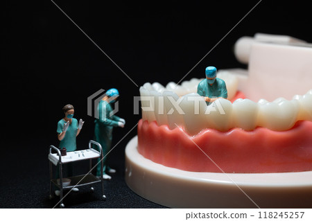 Miniature figurines of surgeons working on a large model of human teeth 118245257