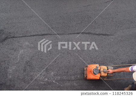Porto, Portugal - 2024, September 1: Close-up of a worker operating a machine compacting asphalt on a fresh road. Concept of repair work in old historical cities, urban development technologies 118245326